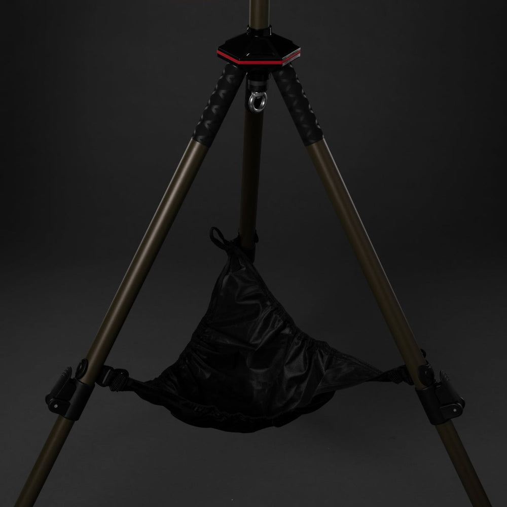 Black bag hanging from a tripod against a dark background