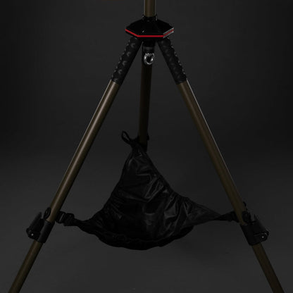 Black bag hanging from a tripod against a dark background
